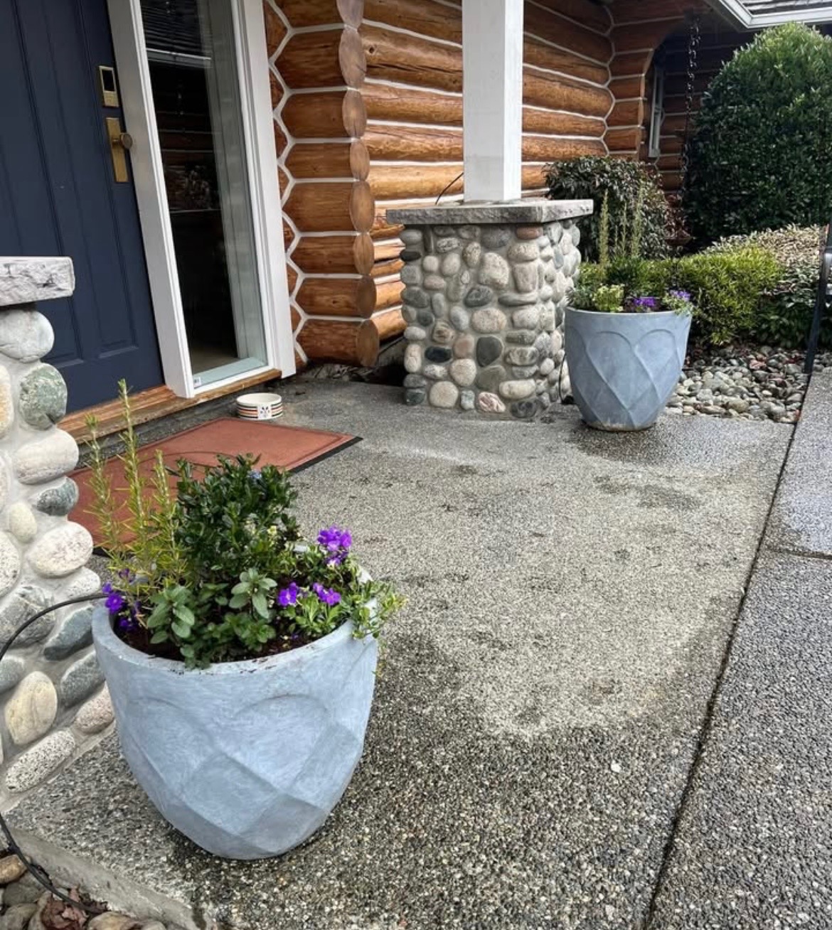 Side view of a grey concrete spring planter at a Nanaimo log home walkway